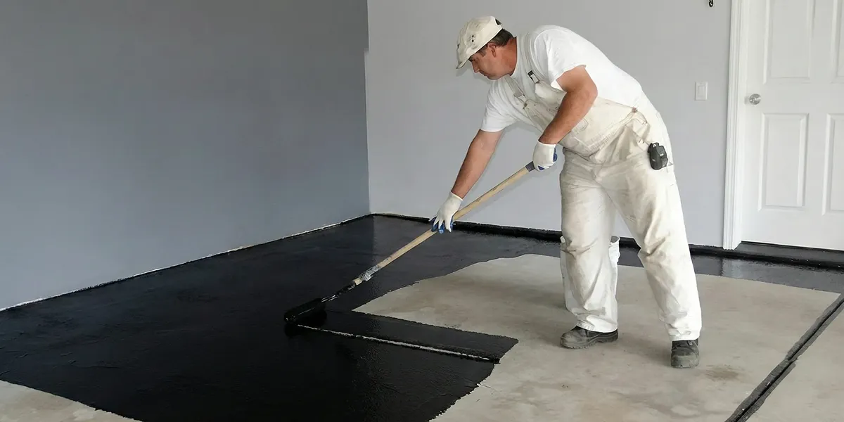 basement waterproofing professional applying waterproof coating to protect a basement floor in Grand Rapids, MI